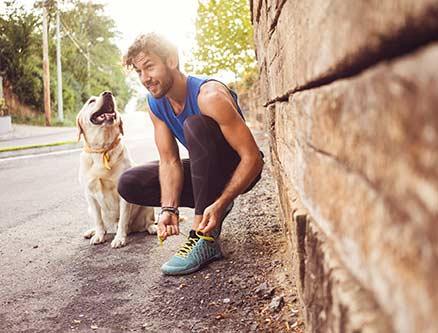 Build up your credit score man ties shoe with dog at his side
